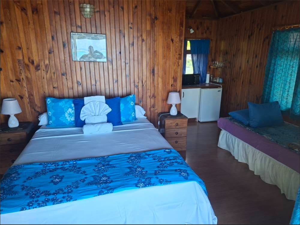 Intérieur du bungalow : lit double, parures bleues, kitchenette