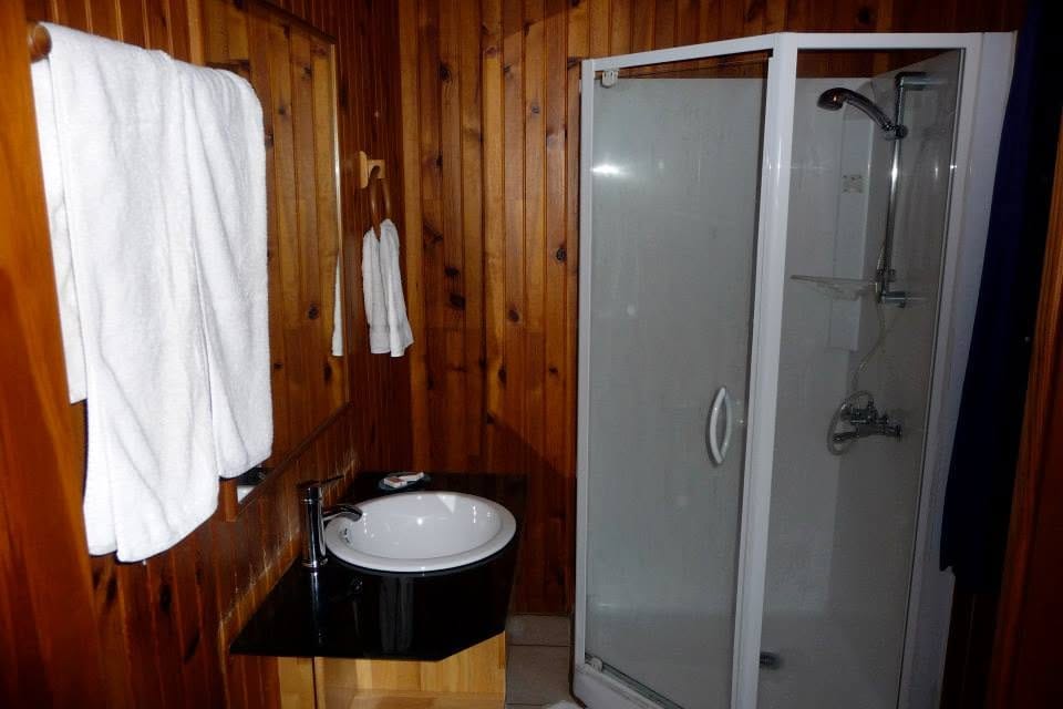 Salle d'eau lambrissée : cabine de douche et vasque